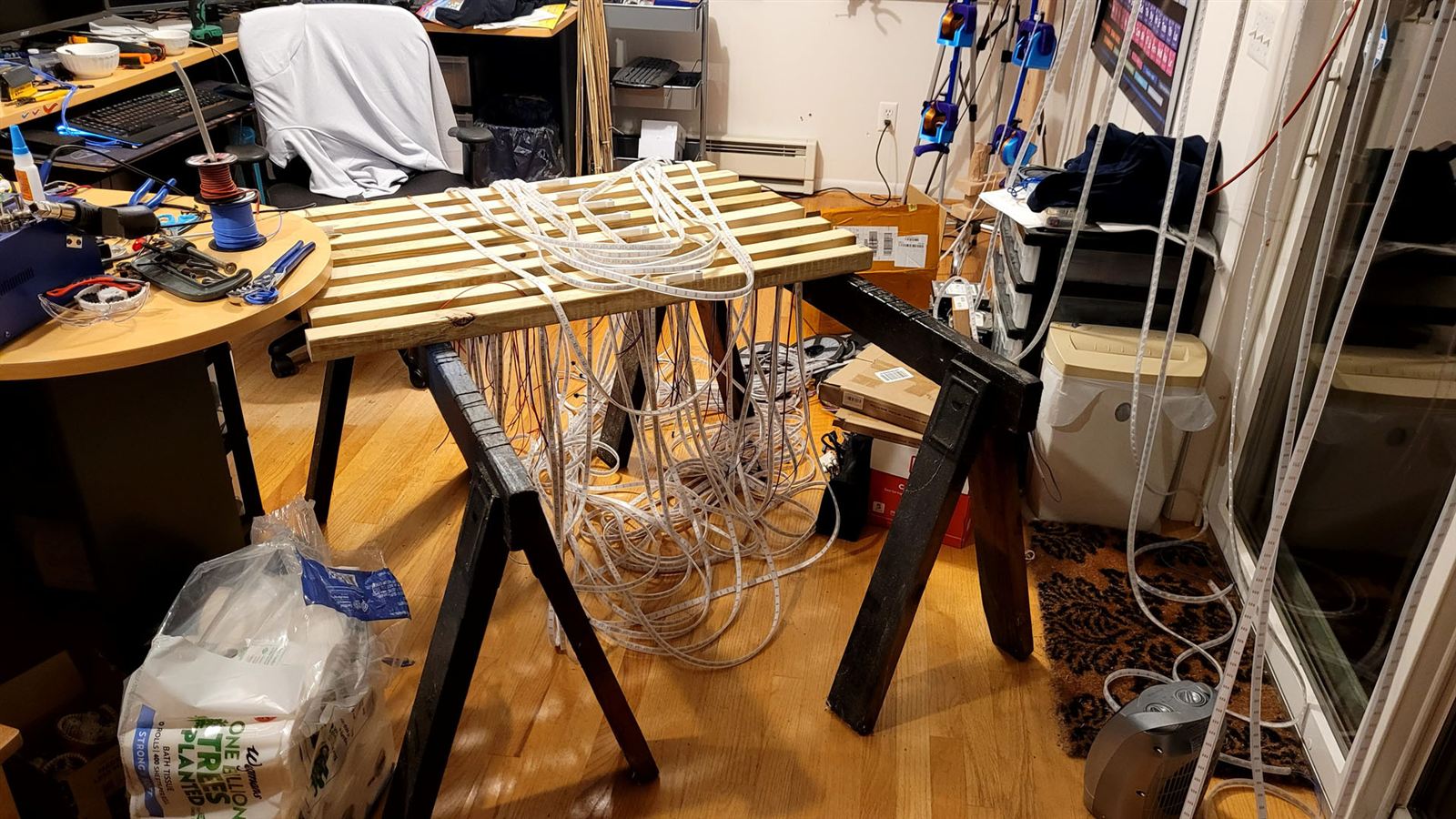 Wooden lattice panel on sawhorses with LED strips draped over it