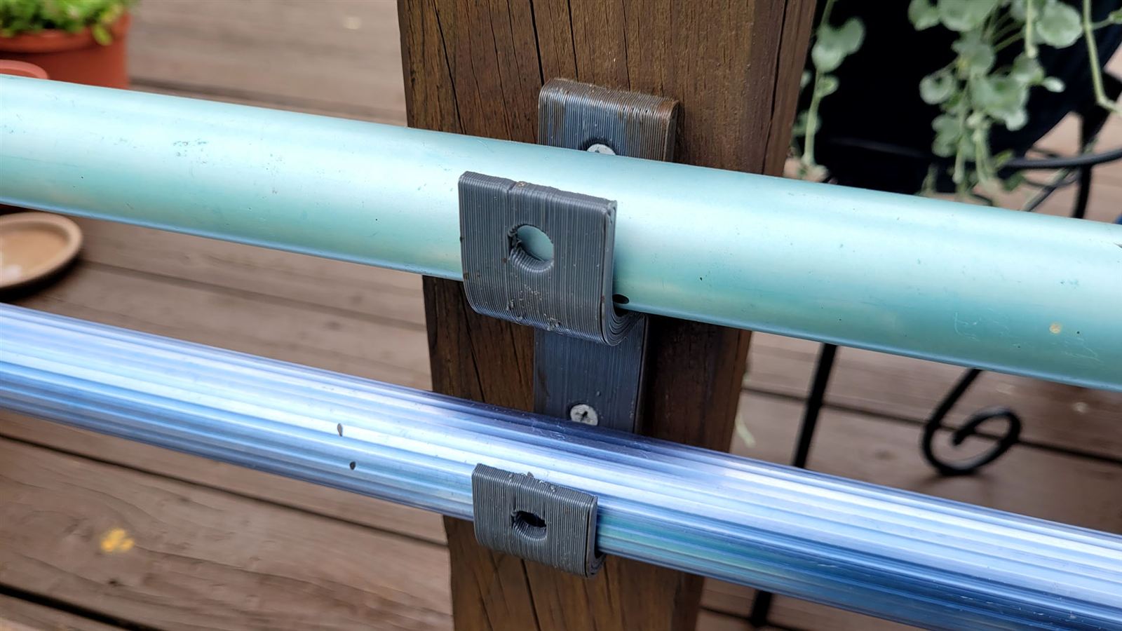 3D printed holder gripping a pool brush and skimmer outdoors